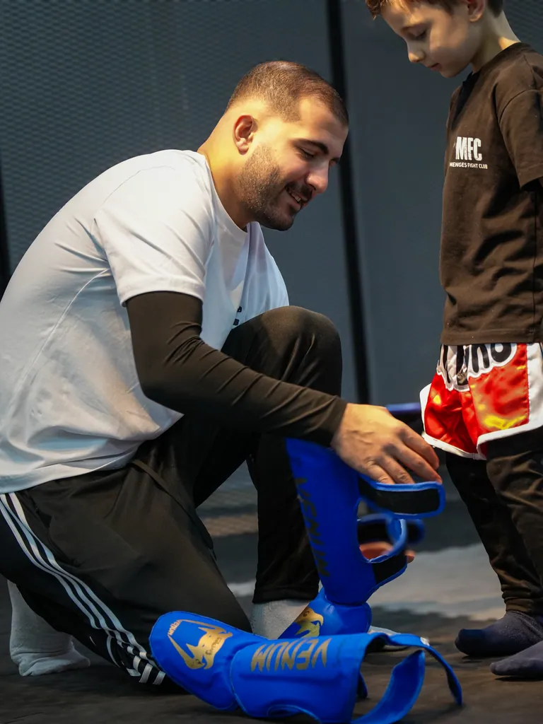 İbrahim Mengeş çocuk sporcunun koruyucu ekipmanını kontrol ediyor